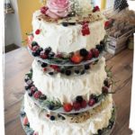 Hochzeitstorte auf Säulenetagere mit bunten Früchten und Thymian